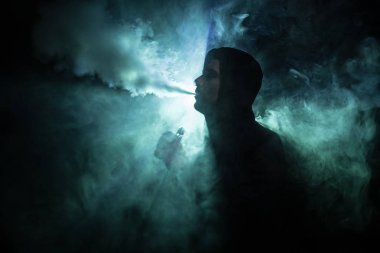 Bir mod tutarak Vaping adam. Buhar bulutu. karanlık sisli bulutlar duman arka plan tonda. Vaping elektronik sigara duman bir sürü ile. Vape kavramı. Seçici odak