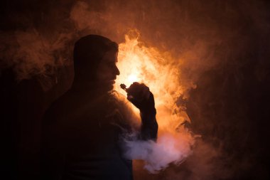 Bir mod tutarak Vaping adam. Buhar bulutu. karanlık sisli bulutlar duman arka plan tonda. Vaping elektronik sigara duman bir sürü ile. Vape kavramı. Seçici odak