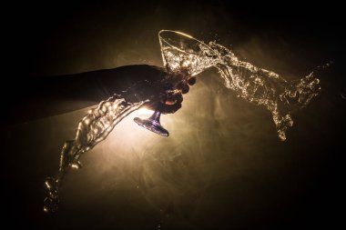 Martini kokteyl cam el koyu tonda dumanlı arka plan veya renkli kokteyl cam su sıçramalarına ve zeytin sıçramasına. Parti club eğlence. Karışık ışık. Seçici odak