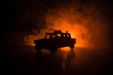 Koyu tonda sisli arka plan üzerinde askeri devriye arabası. Ordu savaş kavramı. Eylemde silahlı ve zırhlı silüeti. Dekore edilmiş. Seçici odak