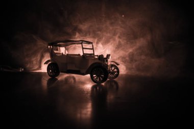 Eski eski model araba içinde karanlık sisli silüeti düşük ışıkta parlayan ışıklar ile arka plan tonda. Seçici odak