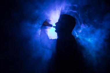 Bir mod tutarak Vaping adam. Buhar bulutu. karanlık sisli bulutlar duman arka plan tonda. Vaping elektronik sigara duman bir sürü ile. Vape kavramı. Seçici odak
