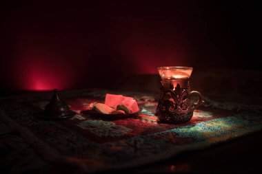 Cam bir halı ile ışık ve duman koyu arka plan üzerinde Doğu snacks ile Arap tea. Doğu çay kavramı. Boş alanı. Seçici odak.