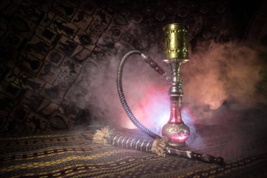 Nargile kömürü nargile kupa Arap iç de buhar bulutları yapma. Şark süsleme halı üzerinde. Şık oryantal shisha içinde karanlık arka ışık ile. Shisha reklam için. Seçici odak