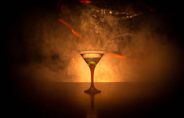 杯子里放着马丁尼 里面放着橄榄 在暗雾蒙蒙的背景下 用酒吧酒来近距离观察玻璃杯 有选择的重点 俱乐部饮料概念 — 图库照片