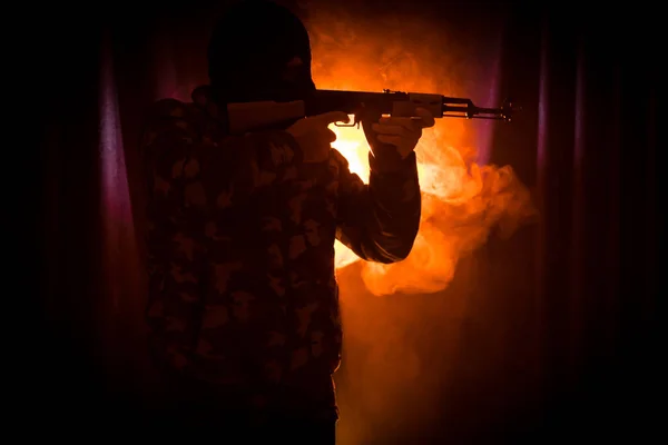 男子与突击步枪的剪影准备攻击黑暗色调的雾背景或危险的强盗身着黑色巴拉克拉瓦和手持枪在手 射击恐怖分子与武器主题装饰 — 图库照片