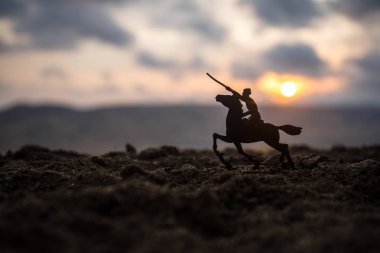 Dünya Savaşı'ndan memur (ya da savaşçı) binici savaşmaya hazır bir kılıçla ata ve askerler bir karanlık sisli gün batımı arka plan tonda. Savaş sahne savaş askerler mücadele. Seçici odak
