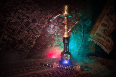Nargile kömürü nargile kupa Arap iç de buhar bulutları yapma. Şark süsleme halı üzerinde. Şık oryantal shisha içinde karanlık arka ışık ile. Shisha reklam için. Seçici odak