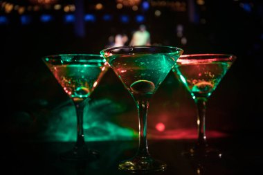 Ünlü kokteyl Martini, birkaç bardak koyu tonda sisli arka plan ve disko ışıkları ile bir barda vurdu. Club içki kavramı. Seçici odak