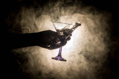Martini kokteyl cam el koyu tonda dumanlı arka plan veya renkli kokteyl cam su sıçramalarına ve zeytin sıçramasına. Parti club eğlence. Karışık ışık. Seçici odak