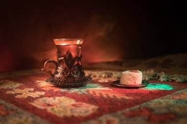 Cam bir halı ile ışık ve duman koyu arka plan üzerinde Doğu snacks ile Arap tea. Doğu çay kavramı. Boş alanı. Seçici odak.