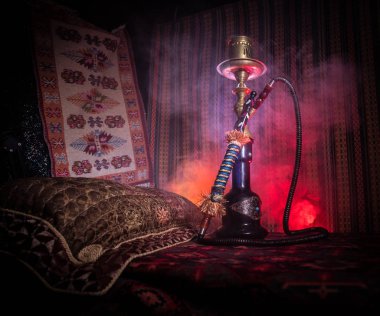 Nargile kömürü nargile kupa Arap iç de buhar bulutları yapma. Şark süsleme halı üzerinde. Şık oryantal shisha içinde karanlık arka ışık ile. Shisha reklam için. Seçici odak