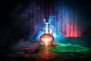 Antique and vintage glass bottle on dark foggy background with light. Poison or magic liquid concept. clipart