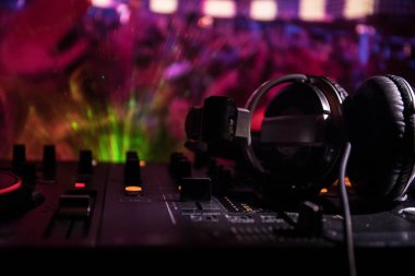 In selective focus of Pro dj controller.The DJ console deejay mixing desk at music party in nightclub with colored disco lights. Close up view clipart