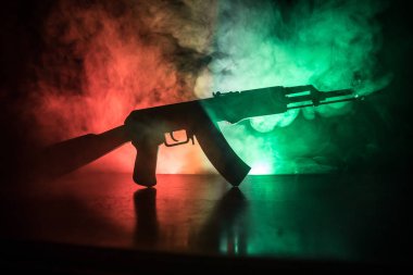 Silhouette of assault rifle on toned foggy background. War or antiterrorism concept. Russian military weapon on table. clipart