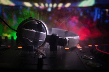 In selective focus of Pro dj controller.The DJ console deejay mixing desk at music party in nightclub with colored disco lights. Close up view clipart