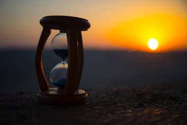 Kum saati geçen zaman atlamalı bulutlar. Bir kum saati önünde parlak mavi gökyüzü ile kabarık beyaz bulutlar geçiyor. Zaman kavramı. Günbatımı zamanı. Seçici odak