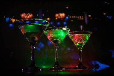 Ünlü kokteyl Martini, birkaç bardak koyu tonda sisli arka plan ve disko ışıkları ile bir barda vurdu. Club içki kavramı. Seçici odak
