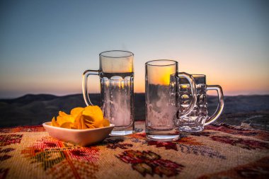 Boş bardağı bira dağlar bir gündoğumu zemin üzerine kapatın. Bira partisi kavram üzerinde var. Seçici odak