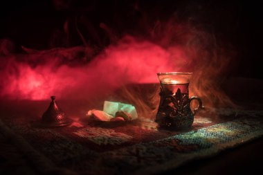 Cam bir halı ile ışık ve duman koyu arka plan üzerinde Doğu snacks ile Arap tea. Doğu çay kavramı. Boş alanı. Seçici odak.