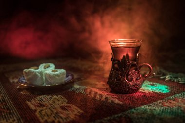 Cam bir halı ile ışık ve duman koyu arka plan üzerinde Doğu snacks ile Arap tea. Doğu çay kavramı. Boş alanı. Seçici odak.