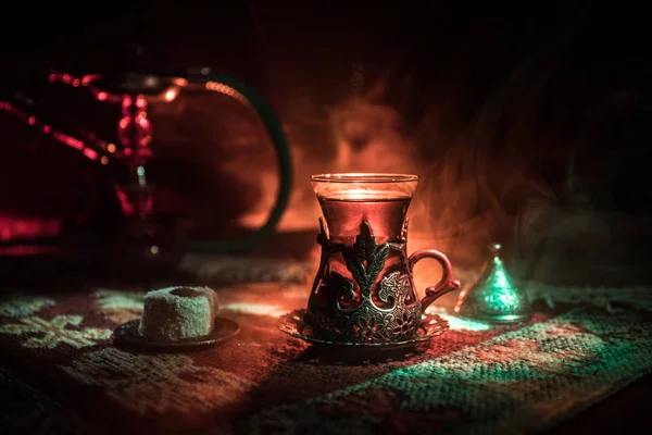 Nargile kömürü nargile kupa Arap iç de buhar bulutları yapma. Şark süsleme halı Doğu çay töreni üzerinde. Şık oryantal shisha içinde karanlık arka ışık ile. Seçici odak
