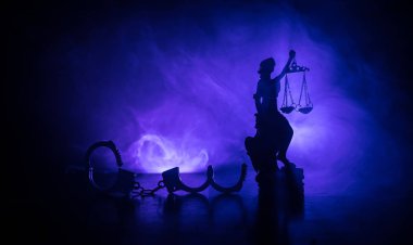 Legal law concept. Silhouette of handcuffs with The Statue of Justice on backside with the flashing red and blue police lights at foggy background. Selective focus clipart