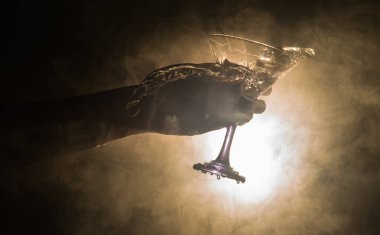 Martini kokteyl cam el koyu tonda dumanlı arka plan veya renkli kokteyl cam su sıçramalarına ve zeytin sıçramasına. Parti club eğlence. Karışık ışık. Seçici odak