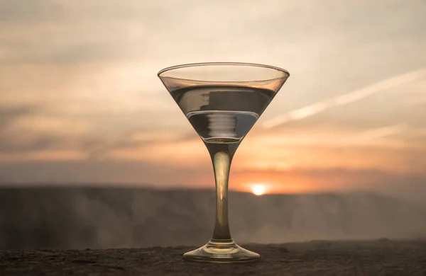 Martini i ett glas mot solnedgången bakgrund med bergen. Club drink i solnedgång — Stockfoto