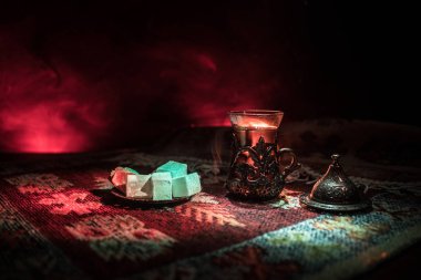 Cam bir halı ile ışık ve duman koyu arka plan üzerinde Doğu snacks ile Arap tea. Doğu çay kavramı. Boş alanı. Seçici odak.