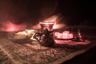 Cam bir halı ile ışık ve duman koyu arka plan üzerinde Doğu snacks ile Arap tea. Doğu çay kavramı. Boş alanı. Seçici odak.