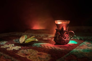 Cam bir halı ile ışık ve duman koyu arka plan üzerinde Doğu snacks ile Arap tea. Doğu çay kavramı. Boş alanı. Seçici odak.