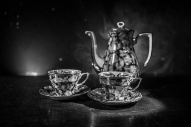 Kahve veya çay töreni kavramsal tema. Eski vintage Seramik çay veya kahve kabı ile cups ışık ve duman ile koyu tonlu arka plan üzerinde. Metin için boş yer. Seçici odak