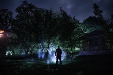 Adam gece ormanda silüeti. Işık ile karanlık ormanın içinde duran kişi silüeti. Karanlık gece ormanda. Gerçeküstü gece orman sahne. Korku Cadılar Bayramı kavramı.