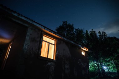 Binanın Orman geceleri ay veya vintage kır evi ile bulutlar ve yıldız ile gece dağ gece manzarası. Yaz gecesi. Uzun pozlama ile çekilen fotoğraf