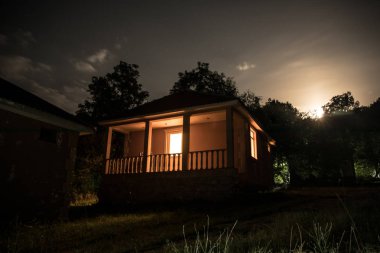Binanın Orman geceleri ay veya vintage kır evi ile bulutlar ve yıldız ile gece dağ gece manzarası. Yaz gecesi. Uzun pozlama ile çekilen fotoğraf