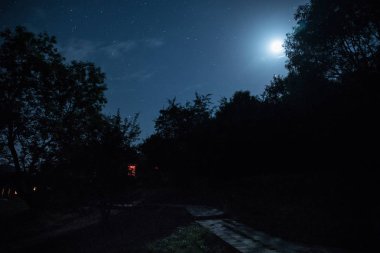 Binanın Orman geceleri ay veya vintage kır evi ile bulutlar ve yıldız ile gece dağ gece manzarası. Yaz gecesi. Uzun pozlama ile çekilen fotoğraf