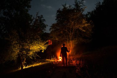 Adam gece ormanda silüeti. Işık ile karanlık ormanın içinde duran kişi silüeti. Karanlık gece ormanda. Gerçeküstü gece orman sahne. Korku Cadılar Bayramı kavramı.