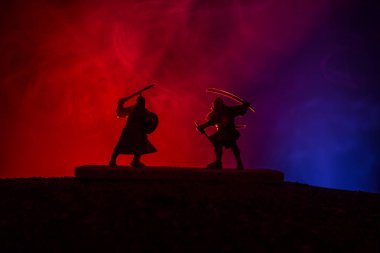 Düelloda iki Ortaçağ savaşçıları silüeti. Karanlık kılıçla ile iki savaşçı resimle sisli arka plan tonda. Seçici odak.