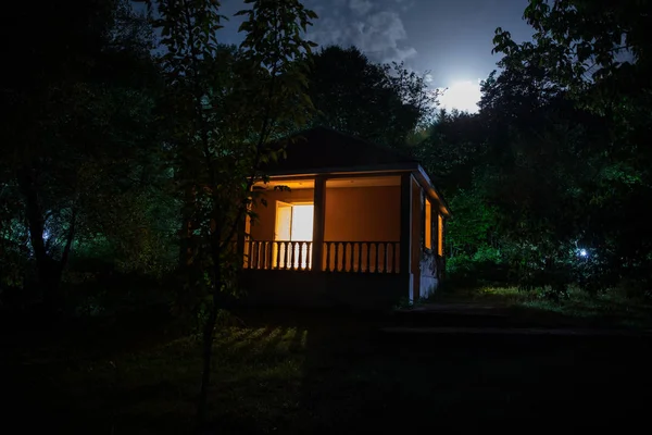 Binanın Orman geceleri ay veya vintage kır evi ile bulutlar ve yıldız ile gece dağ gece manzarası. Yaz gecesi. Uzun pozlama ile çekilen fotoğraf