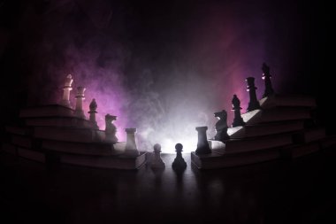 İş hiyerarşisi. Satranç taşları ile strateji kavramı. Kralın üst bir piramit kitapların üzerinde dururken satranç. Tonda ışık ile karanlık sisli arka plan. Kopya alanı.