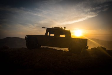 Gün batımı arka plan üzerinde askeri devriye arabası. Ordu savaş kavramı. Eylemde silahlı ve zırhlı silüeti. Dekore edilmiş. Seçici odak