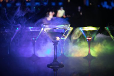 Ünlü kokteyl Martini, birkaç bardak koyu tonda sisli arka plan ve disko ışıkları ile bir barda vurdu. Club içki kavramı. Seçici odak