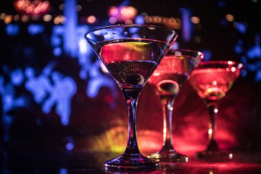 Ünlü kokteyl Martini, birkaç bardak koyu tonda sisli arka plan ve disko ışıkları ile bir barda vurdu. Club içki kavramı. Seçici odak