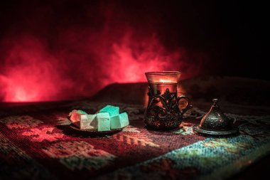 Cam bir halı ile ışık ve duman koyu arka plan üzerinde Doğu snacks ile Arap tea. Doğu çay kavramı. Boş alanı. Seçici odak.
