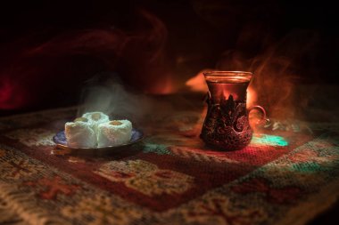 Cam bir halı ile ışık ve duman koyu arka plan üzerinde Doğu snacks ile Arap tea. Doğu çay kavramı. Boş alanı. Seçici odak.