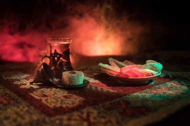 Cam bir halı ile ışık ve duman koyu arka plan üzerinde Doğu snacks ile Arap tea. Doğu çay kavramı. Boş alanı. Seçici odak.