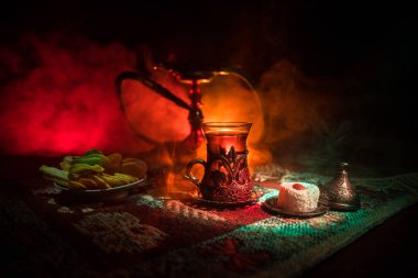 Nargile kömürü nargile kupa Arap iç de buhar bulutları yapma. Şark süsleme halı Doğu çay töreni üzerinde. Şık oryantal shisha içinde karanlık arka ışık ile. Seçici odak