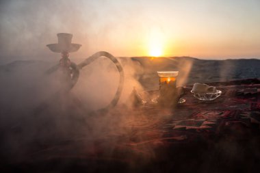 Nargile kömürü nargile kupa çöl de buhar bulutları açık yapma. Şark süsleme halı Doğu çay töreni üzerinde. Şık oryantal shisha günbatımı arka plan üzerinde. Seçici odak