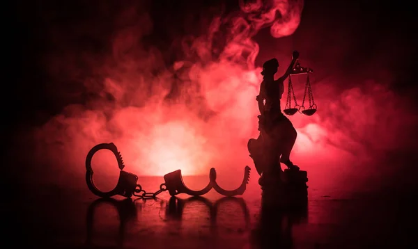 法律法律概念 手铐的剪影与正义雕像背面与闪烁的红色和蓝色警察灯在雾背景 选择性聚焦 — 图库照片